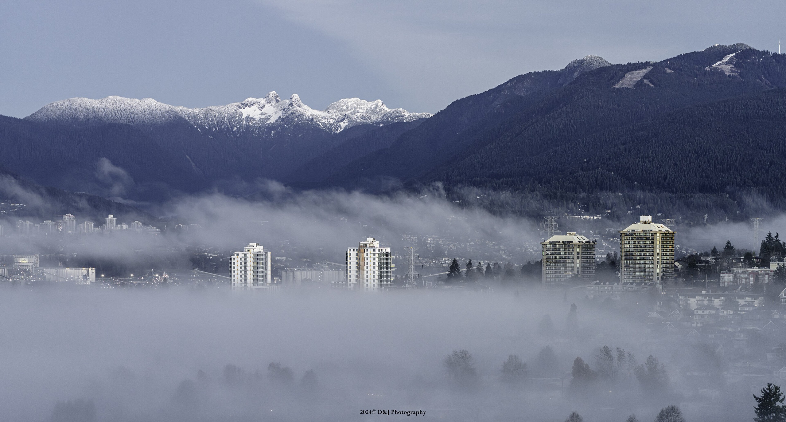 Low fog over Vancouver with the snow-capped North Shore mountains behind